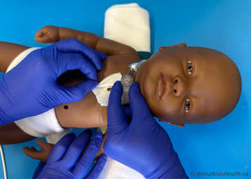 Main person is holding the tracheostomy tube in place while the assistant removes the gauze