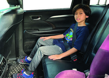 Teen sitting in a car, wearing a seatbelt