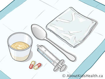 plastic bag, medicine cup containing apple sauce, spoon, oral syringe, and capsules on a mat