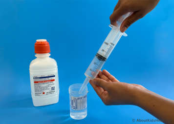 saline being drawn up from a syringe from a sterile container