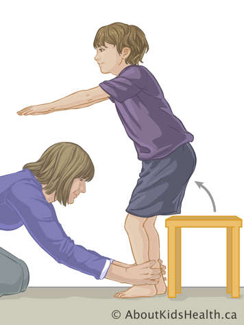 Child standing up from stool while parent holds their ankles