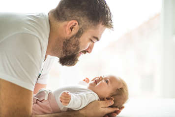 Father holding and looking at newborn baby