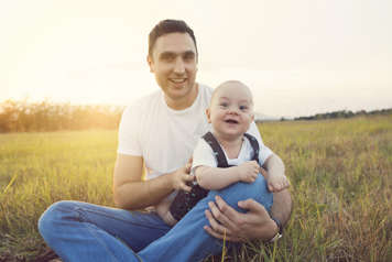 Father with baby lying across his legs