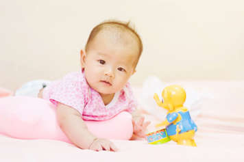 Baby showing tummy time with a roll under their arms