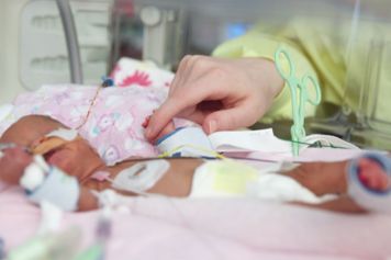 An infant holding its parent's index finger