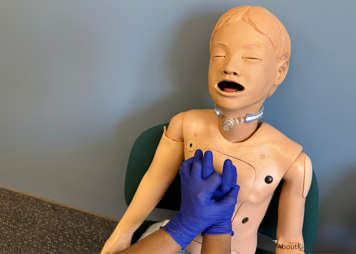 Caregiver's other hand placed over first hand and fingers are interlocked and pulled away from the body