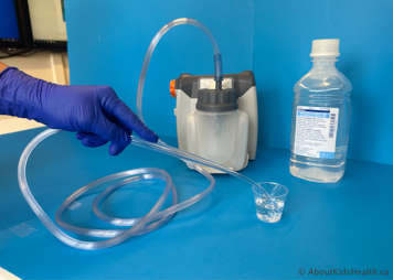 Yankauer being dipped in sterile water to flush it