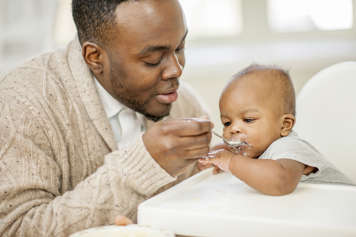 Father feeding baby in high chair