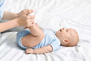 baby lying down and mother holding baby's feet