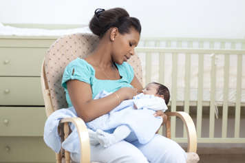 Mother sitting in rocking chair feeding baby