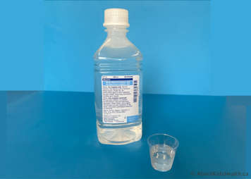 A sterile water bottle and a labelled cup of sterile water for suctioning