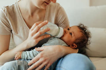 Woman holding baby on her lap and feeding the baby a bottle