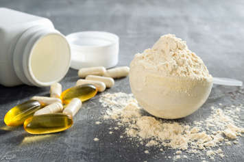 Scoop of beige powder and a bottle lying on its side with capsules near it