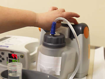 Person pressing the on and off switch on a suction machine