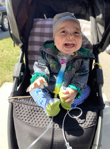 Child with a tracheostomy using oxygen therapy sitting in a stroller